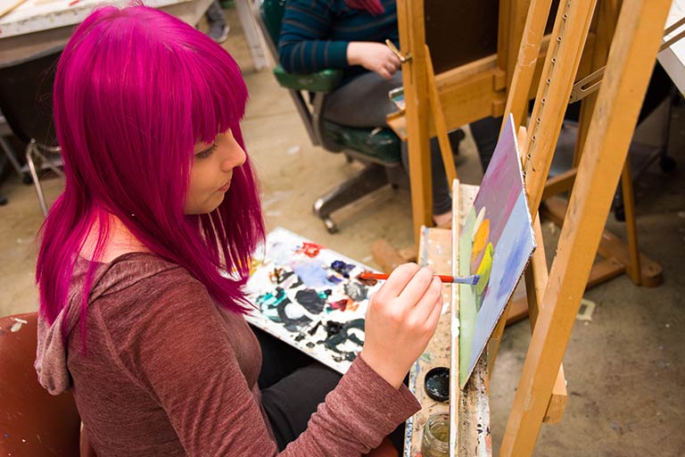 A student painting at an easel 