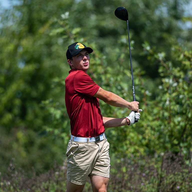 IU East men's golf athlete just after hitting the ball as it flies towards the green.
