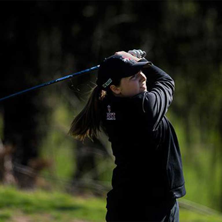 IU East women's golf athlete watching the ball fly after hitting it.